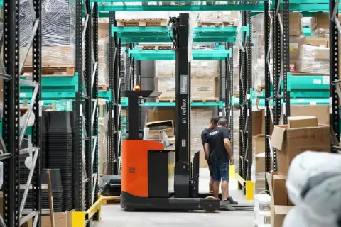 Wózek widłowy w magazynie, pracownicy przygotowują towar do wysyłki. Efektywny outbound logistics.